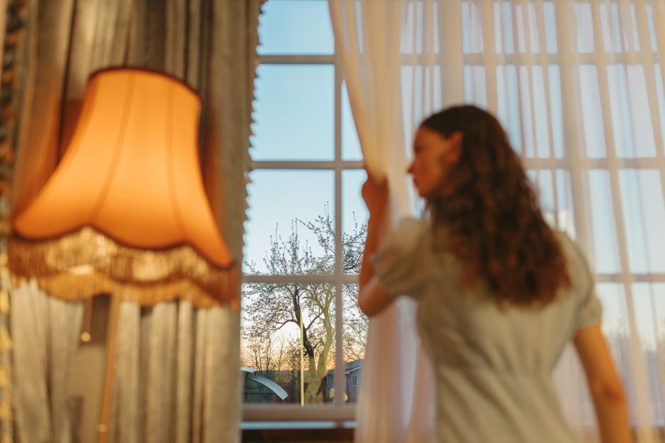 Woman adjusting elegant window shades in a sunlit room